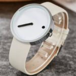 Montre moderne au design épuré avec cadran blanc et bracelet beige, idéale pour les amateurs de style simple et élégant. Parfaite pour une décoration de bureau ou un accessoire de mode original.