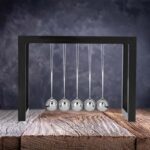 Balle de Newton en acier inoxydable suspendue, idéale pour expériences de physique et décoration scientifique moderne. Parfait pour illustrer la conservation de l'énergie et la dynamique.
