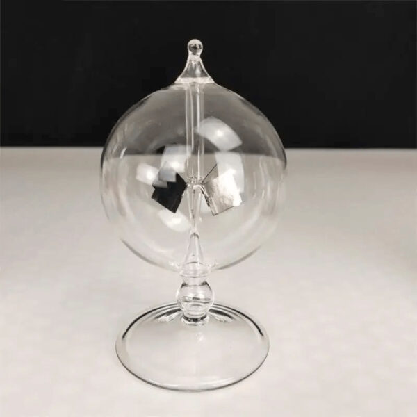 Boule à pendule en verre transparent avec mécanisme suspendu, décor scientifique élégant, sur fond noir et blanc.