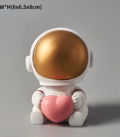 Figurine d'astronaute mignonne tenant un cœur en peluche rose, idéale pour la décoration scientifique et ludique.