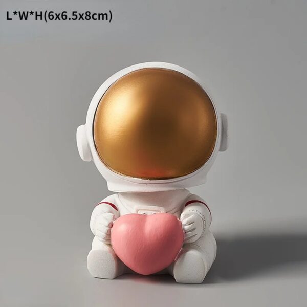 Figurine d'astronaute mignonne tenant un cœur en peluche rose, idéale pour la décoration scientifique et ludique.