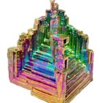 Pyramide de cristaux d'arséniure d'indium iridescente, objet scientifique décoratif aux couleurs vibrantes et à la structure géométrique complexe.
