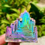 Pièce décorative en métal iridescent avec un design géométrique en escalier, idéale pour la décoration intérieure ou comme objet de collection scientifique.