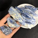 Pierre de saphir brute avec différentes nuances de bleu, présentée dans une main et sur une assiette, idéale pour la décoration scientifique ou la collection minéralogique.