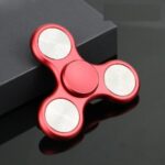 Accessoire de détente et de concentration, fidget spinner rouge en métal avec trois branches et roulements en acier. Parfait pour réduire le stress et améliorer la concentration.