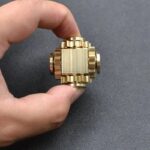 Pendentif en métal doré avec design mécanique complexe, inspiré de la science et de la technologie, parfait pour la décoration ou comme bijou original.