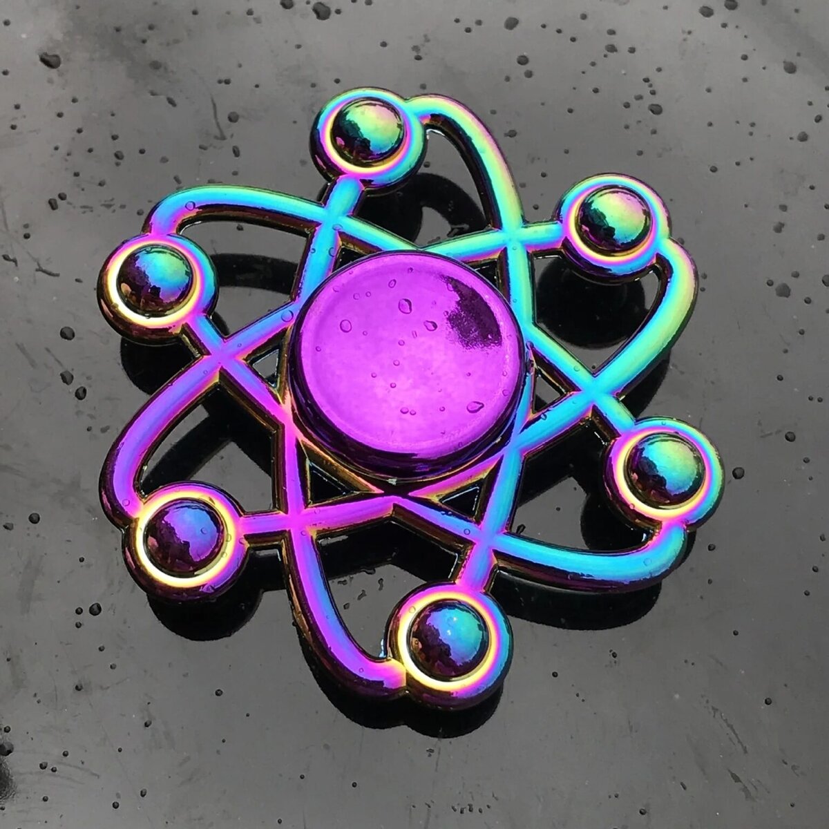Atome en métal coloré avec effet holographique, symbole scientifique décoratif.