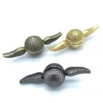 Porte-clés original en forme de capsule avec ailes en métal doré et argenté.