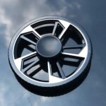 Pneu de voiture avec jantes en alliage noir et argent, vue de dessus sur une surface réfléchissante.