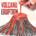 Modèle réduit de volcan en éruption avec lave rougeâtre coulant du sommet, illustrant un phénomène géologique spectaculaire.