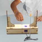 Expérience scientifique avec fils, ampoule et support en bois pour apprendre l'électricité.