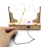 Montage d'une expérience électrique avec un générateur de courant, une bobine et une LED, illustrant un circuit simple pour démonstration scientifique.