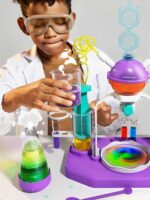 Jeune garçon portant des lunettes de protection effectuant une expérience scientifique avec un kit de laboratoire coloré et interactif.
