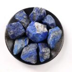 Pierre de lapis lazuli brute, pierres naturelles de couleur bleue avec des inclusions blanches et dorées, présentée dans un bol noir.