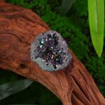 Pierres météoritiques avec cristaux colorés et scintillants sur un morceau de bois naturel.