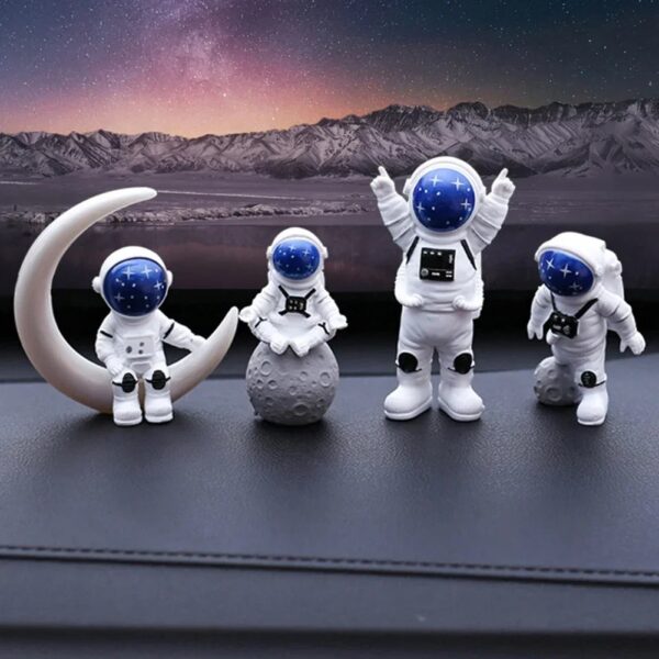 Quatre figurines d'astronautes en décoration, avec un décor lunaire et montagneux en arrière-plan, parfaites pour une décoration thématique scientifique ou spatiale.