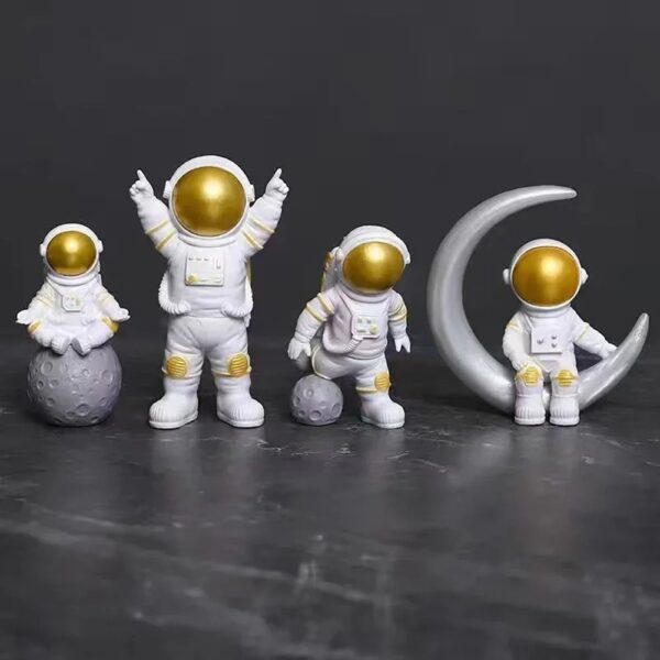 Quatre figurines d'astronautes en décoration, avec des casques dorés et des costumes blancs, accompagnées d'une lune en décoration, parfaites pour un thème spatial ou scientifique.