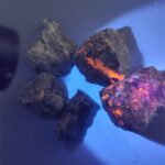 Pierre de météorite sous lumière UV avec fluorescence orange et violette.