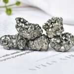 Groupe de cristaux de pyrite naturels avec une surface métallique brillante, disposés sur une feuille de papier blanc, illustrant la beauté minérale et la structure géologique unique.