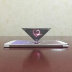Cœur lumineux en 3D flottant au-dessus d'un smartphone, création artistique avec effets lumineux et technologie moderne.
