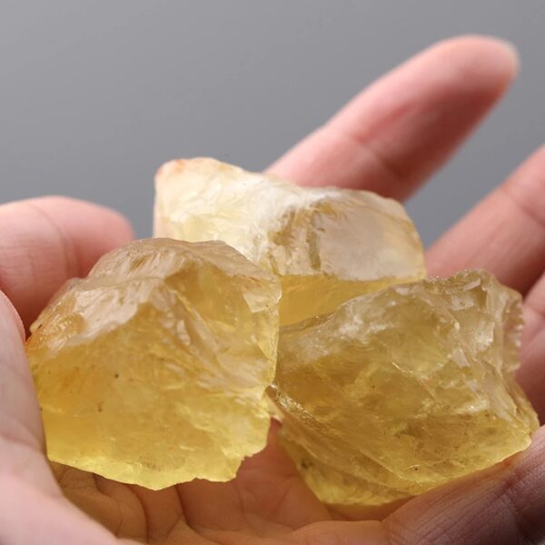 Cristal de résine jaune translucide, brut et naturel, tenu entre les doigts. Parfait pour la décoration ou la collection d'objets scientifiques.