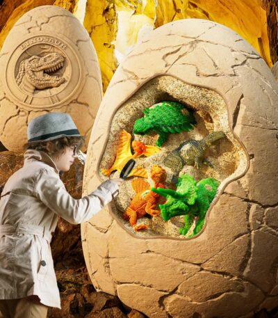 Enfant jouant avec des figurines de dinosaures dans une grotte thématique, décorée avec des éléments de roche et un logo de dinosaure en pierre.