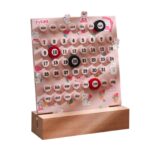 Un calendrier mural en bois avec des boutons rotatifs pour indiquer les jours, mois et dates, décoré de motifs mignons de lapins et fleurs.
