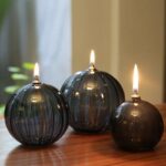 Bougies décoratives en forme de sphère en verre noir avec flamme allumée, parfaites pour une décoration moderne et élégante.