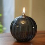 Bougie décorative en verre noir avec flamme allumée, idéale pour une décoration scientifique ou moderne.