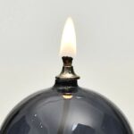 Bougie allumée dans un porte-bougie en verre noir, style scientifique, décoration de laboratoire ou d'intérieur moderne.