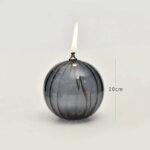 Bougie sphérique en verre noir avec flamme allumée, hauteur 10 cm, design élégant et moderne, idéale pour la décoration scientifique ou d'intérieur.