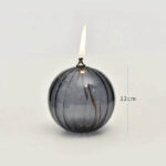Bougie globe en verre noir avec flamme allumée, décoration scientifique originale.