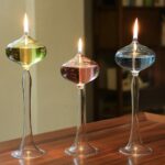 Trois vases de laboratoire en verre contenant des liquides colorés, en feu, sur une surface en bois, illustrant une expérience scientifique ou décoration innovante.