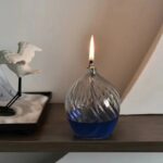 Lampe à huile décorative en verre avec flamme allumée, idéale pour la décoration intérieure et l'ambiance chaleureuse.