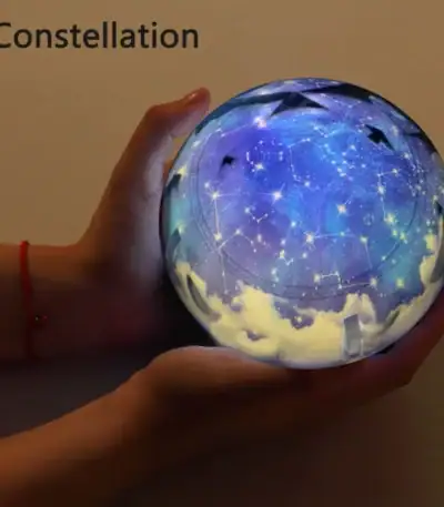 Boule lumineuse représentant une constellation d'étoiles avec un ciel étoilé et des constellations visibles, tenue dans une main pour un effet magique et décoratif.