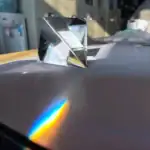 Pyramide en verre prismatique créant un arc-en-ciel de lumière sur une surface plane, illustrant la réfraction et la dispersion de la lumière.