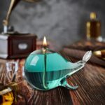Lampe décorative en forme de narval en verre turquoise avec lumière allumée, idéale pour une décoration scientifique ou fantastique.
