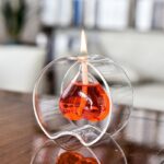 Porte-bougie décoratif en forme de ballon de laboratoire en verre transparent avec liquide rouge et flamme allumée, idéal pour la décoration scientifique ou thématique.