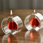 Bougie décorative en forme de cœur rouge dans un support en verre transparent.