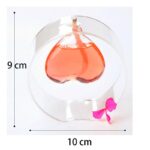 Vase en forme de cœur avec bougie flottante, idéal pour décoration romantique ou scientifique. Dimensions : 9 cm de haut, 10 cm de diamètre, avec un ruban rose décoratif.
