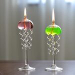 Bougies allumées dans des verreries en forme de méduse avec spirales en verre, utilisées comme décoration de science ou d'objets de collection.