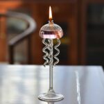 Lampe de bougie en verre avec spirales métalliques décoratives.