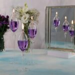 Bougies en forme de flamme dans des verreries en verre transparent avec liquide violet.