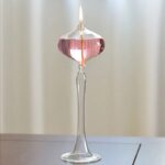 Pied à souffler en verre soufflé avec flamme allumée, utilisé pour la décoration ou la science.