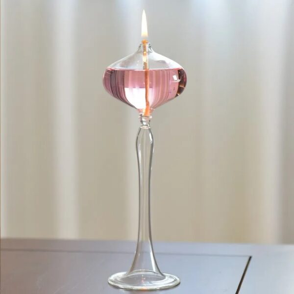 Pied à souffler en verre soufflé avec flamme allumée, utilisé pour la décoration ou la science.