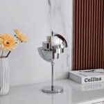 Lampe de bureau design en métal chromé avec une finition brillante, idéale pour une décoration contemporaine et élégante dans un espace de travail ou un salon.