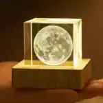 Lampe décorative en forme de pleine lune encadrée dans un cube en verre, posée sur une base en bois, idéale pour une décoration scientifique ou lunaire.