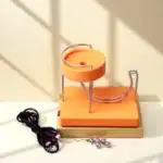 Piste de billard en verre avec billes métalliques et câble électrique, idéale pour la décoration scientifique ou éducative. Un objet original pour les amateurs de science et de design moderne.