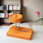 Balancier scientifique en orange avec sphères métalliques, décoration moderne et originale pour un intérieur inspiré de la science.