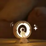 Petite décoration de vaisseau spatial lumineux avec un astronaute en costume blanc, idéale pour une ambiance scientifique ou futuriste.